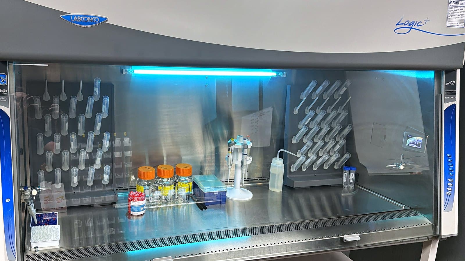 Labconco Class II A2 biosafety cabinet at KMD Analytical, with pipettes, tube racks and reagent bottles on the work surface.