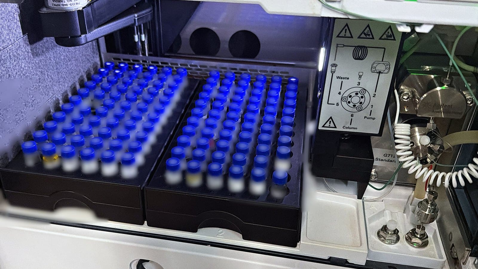 Agilent HPLC autosampler at KMD Analytical: two racks of capped 2 mL vials queued for injection, with the injection-valve panel at right.